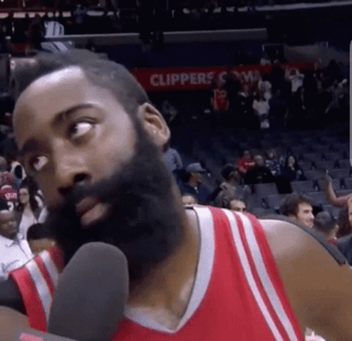 A Basketball Player With A Beard Is Talking Into A Microphone On A Court . GIF