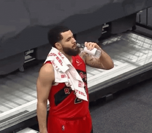 A Basketball Player With A Towel Around His Neck Drinking Water From A Bottle . GIF