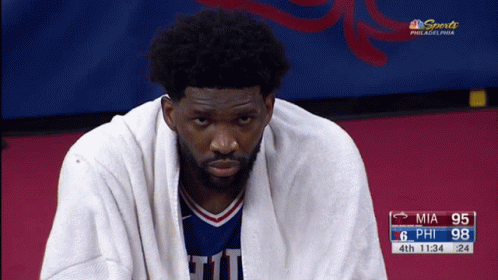 A Basketball Player With A Towel Wrapped Around His Neck Is Sitting On The Court GIF