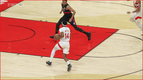 a basketball player with the number 14 on his jersey dribbles the ball