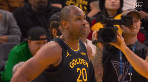 a basketball player with the number 20 on his jersey is being interviewed by a cameraman