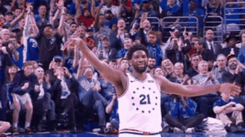 A Basketball Player With The Number 21 On His Jersey Is Standing In Front Of A Crowd GIF