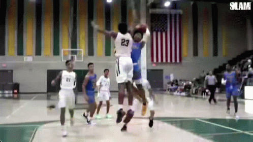 A Basketball Player With The Number 23 On His Jersey Is Jumping Over Another Player GIF