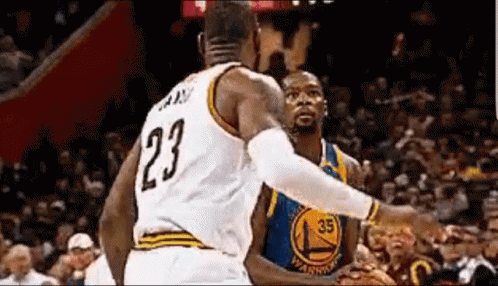 A Basketball Player With The Number 23 On His Jersey Is Standing Next To Another Basketball Player . GIF