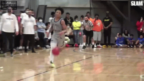 A Basketball Player With The Number 7 On His Jersey Is Dribbling The Ball On A Court GIF