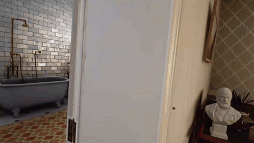 A Bathroom With A Bathtub And A Statue Of A Man On A Table GIF