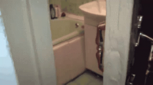 A Bathroom With A Sink And Bathtub And A Door Open GIF