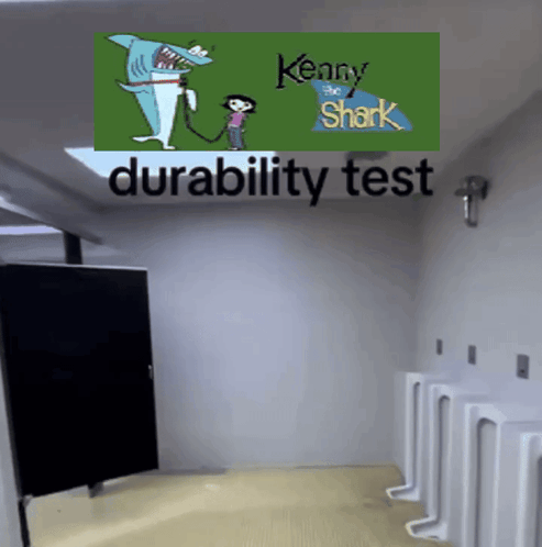 A Bathroom With Urinals And A Kenny The Shark Poster On The Wall GIF