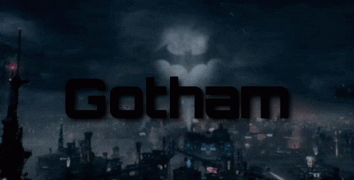 A Batman Logo Is Projected On A City Skyline GIF