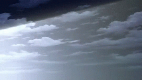 A Beam Of Light Is Shining Through The Clouds In The Sky . GIF