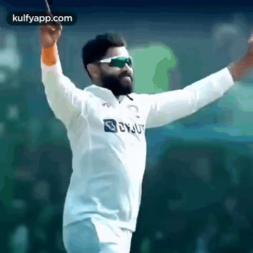 A Bearded Man Wearing Sunglasses And A White Shirt Is Holding A Bat In His Hand . GIF