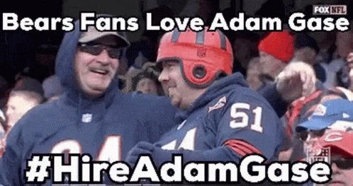 A Bears Fan Wearing A Red Helmet Is Standing Next To Another Fan Wearing A Number 51 Jersey . GIF