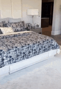 A Bed With A Patterned Blanket And Pillows In A Bedroom GIF