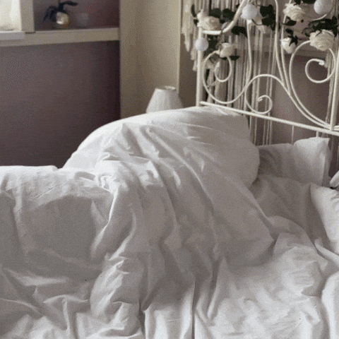 A Bed With White Sheets And Pillows And A White Headboard GIF