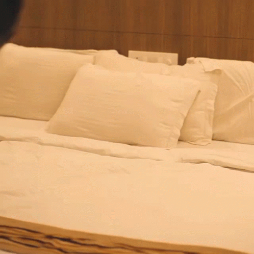 A Bed With White Sheets And Pillows In A Bedroom GIF
