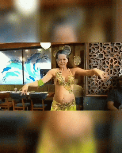 A Belly Dancer Is Dancing In Front Of A Painting Of Dolphins GIF