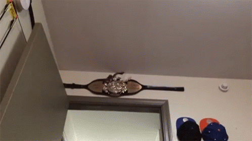 A Belt Is Hanging From The Ceiling In A Room With Hats Hanging On The Wall GIF
