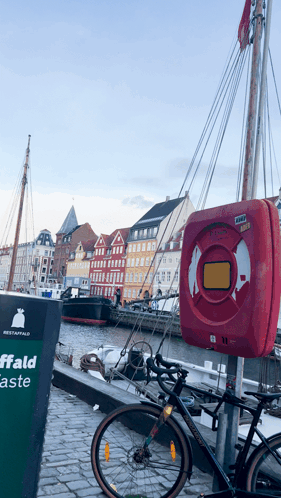 A Bicycle Is Parked Next To A Sign That Says Affald GIF