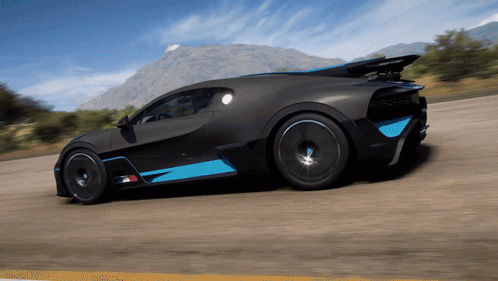 A Black And Blue Sports Car Is Driving On A Road With Mountains In The Background GIF