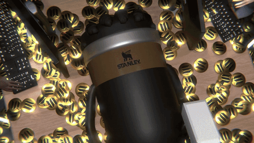 A Black And Gold Stanley Coffee Mug Is Surrounded By Gold Coins GIF