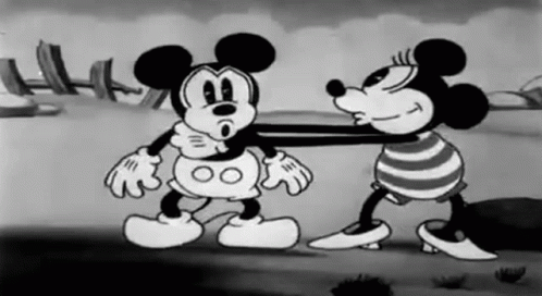 A Black And White Cartoon Of Mickey Mouse And Minnie Mouse Standing Next To Each Other On A Beach . GIF