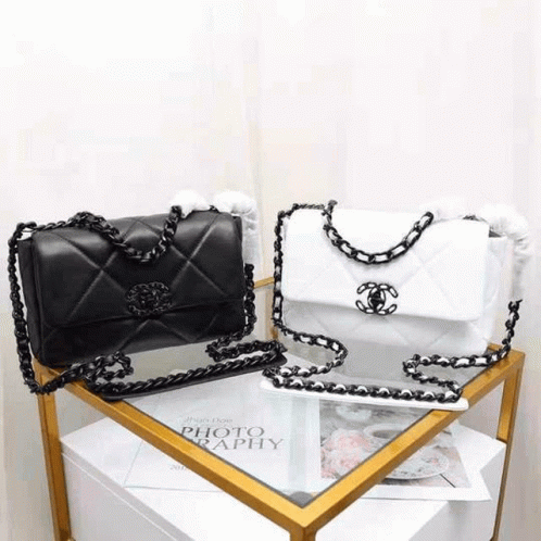 A Black And White Chanel Purse Is Sitting On Top Of A Table . GIF