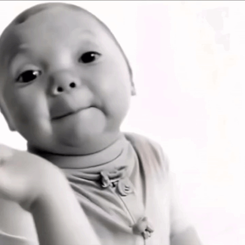A Black And White Photo Of A Baby With A Necklace Around His Neck GIF