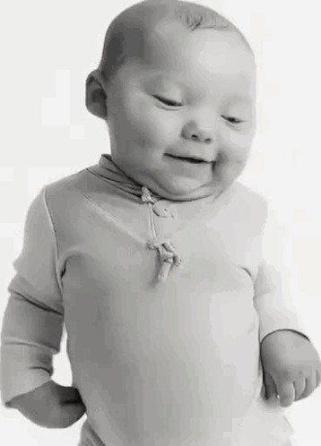 A Black And White Photo Of A Baby With Down Syndrome Smiling . GIF