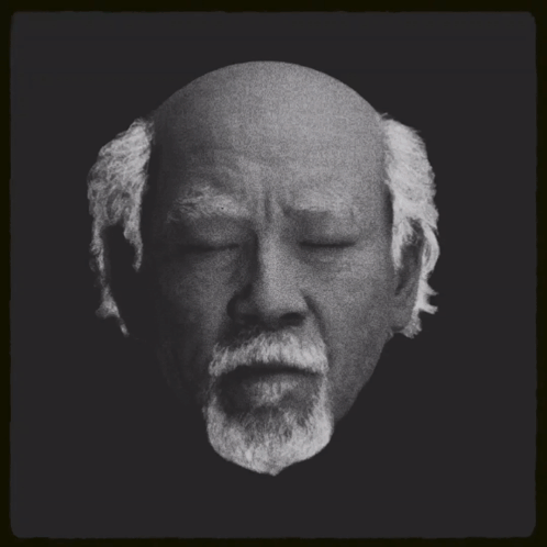 A Black And White Photo Of A Bald Man With A Beard And The Words Miyagi New Buy On The Bottom GIF