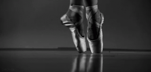 A Black And White Photo Of A Ballerina 'S Feet In Pointe Shoes Jumping In The Air . GIF