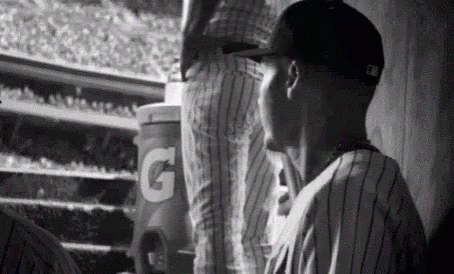 A Black And White Photo Of A Baseball Player In A Dugout . GIF