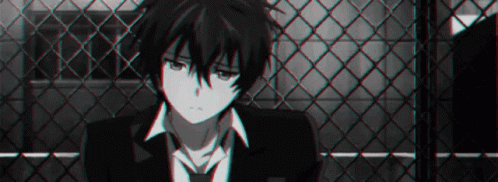 A Black And White Photo Of A Boy In A Suit And Tie Sitting In Front Of A Chain Link Fence . GIF