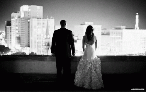 A Black And White Photo Of A Bride And Groom Looking At A City Skyline GIF
