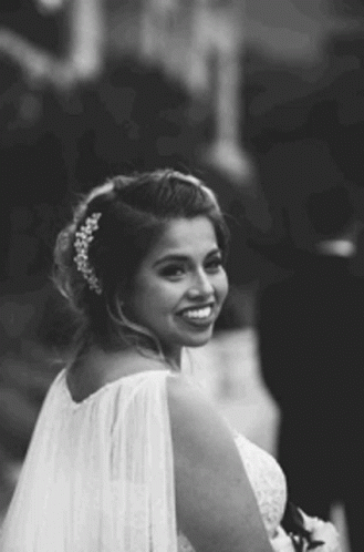 A Black And White Photo Of A Bride In A Wedding Dress And Veil Smiling . GIF