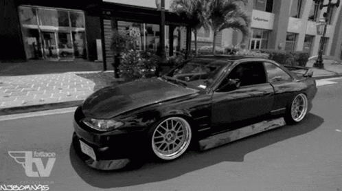 A Black And White Photo Of A Car On A City Street . GIF