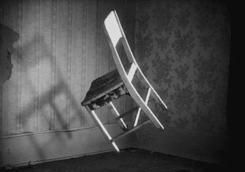 A Black And White Photo Of A Chair That Is Flying Through The Air In A Room . GIF