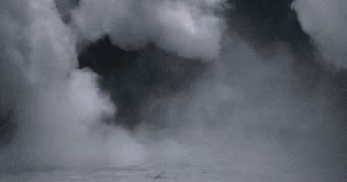 A Black And White Photo Of A Cloudy Sky With A Boat In The Distance . GIF