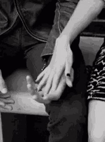 A Black And White Photo Of A Couple Holding Hands . GIF