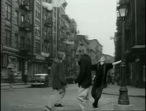 a black and white photo of a couple walking down a street