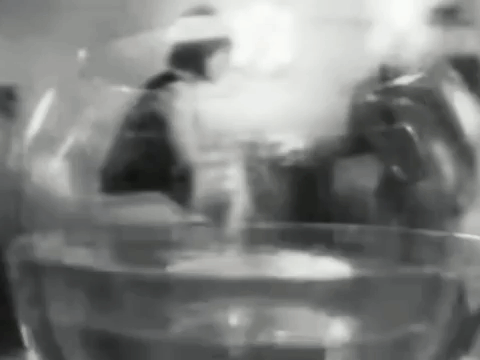 A Black And White Photo Of A Glass Of Water With A Person In The Background . GIF