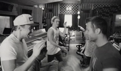 A Black And White Photo Of A Group Of Men In A Recording Studio With One Wearing A Hat That Says Budweiser GIF