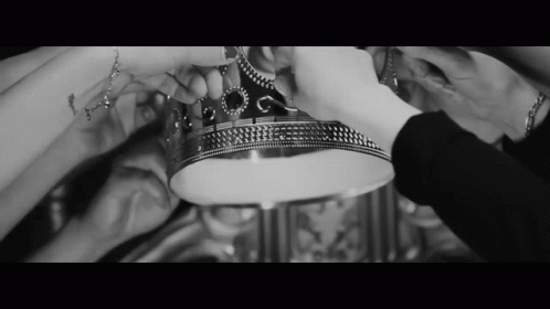 A Black And White Photo Of A Group Of People Holding A Silver Crown GIF