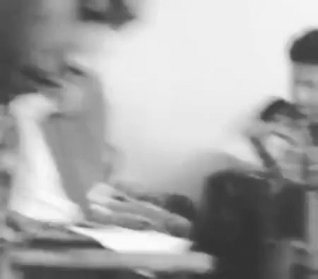 A Black And White Photo Of A Group Of People Sitting At A Table Using Their Phones . GIF
