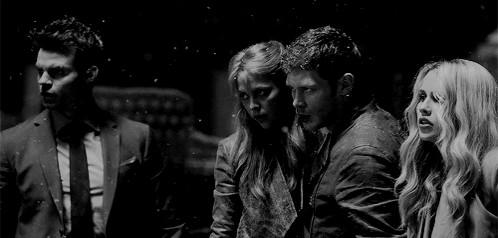 A Black And White Photo Of A Group Of People Standing Next To Each Other In A Dark Room . GIF