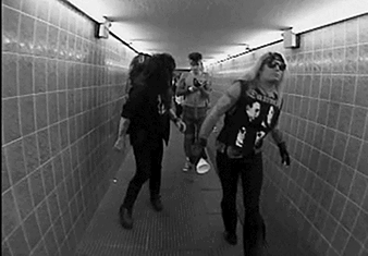 A Black And White Photo Of A Group Of People Walking In A Tunnel . GIF