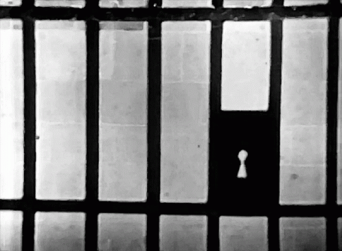 A Black And White Photo Of A Jail Cell With A Keyhole In The Middle GIF