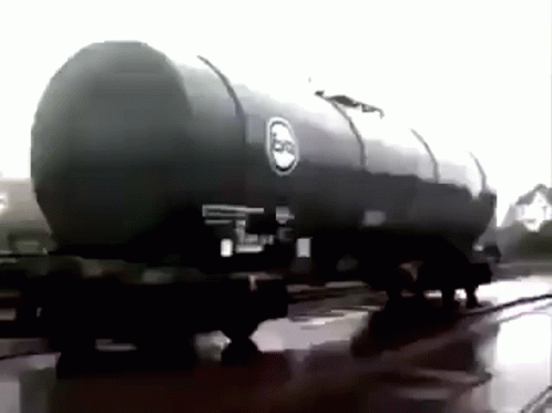 A Black And White Photo Of A Large Oil Tank On A Train Track . GIF