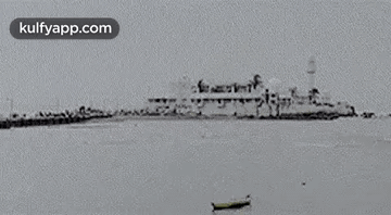A Black And White Photo Of A Large Ship In The Ocean With A Boat In The Foreground . GIF