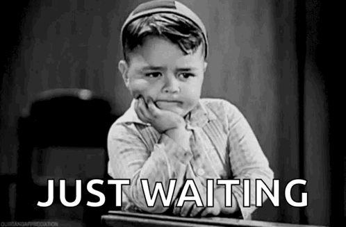 A Black And White Photo Of A Little Boy Sitting At A Desk With His Hand On His Chin And The Words `` Just Waiting '' . GIF