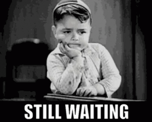 A Black And White Photo Of A Little Boy Sitting At A Desk With The Words `` Still Waiting '' Written Above Him . GIF